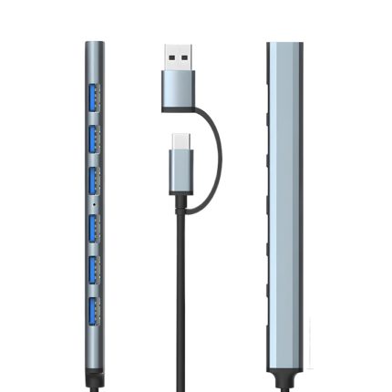 Un hub USB-C gris de aluminio muestra siete puertos USB 3.0 azules y dos conectores laterales con cable negro en fondo blanco.