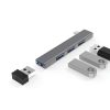 Un hub USB-C gris de aluminio del modelo EON con cuatro puertos USB y conectores USB-A visibles junto a adaptadores metálicos sobre fondo blanco.