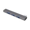 Un hub USB-C gris de aluminio muestra tres puertos USB visibles y un conector macho en un extremo sobre fondo blanco, con diseño compacto.