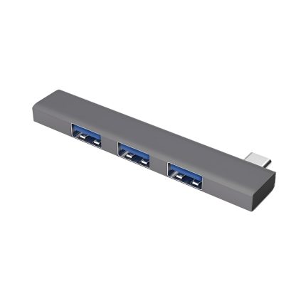 Un hub USB-C gris de aluminio muestra tres puertos USB visibles y un conector macho en un extremo sobre fondo blanco, con diseño compacto.