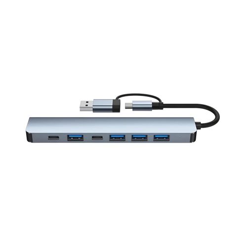 Un hub gris de aluminio con cable USB-C muestra una conexión macho USB y siete puertos, incluidos varios USB y dos USB-C, sobre fondo blanco.