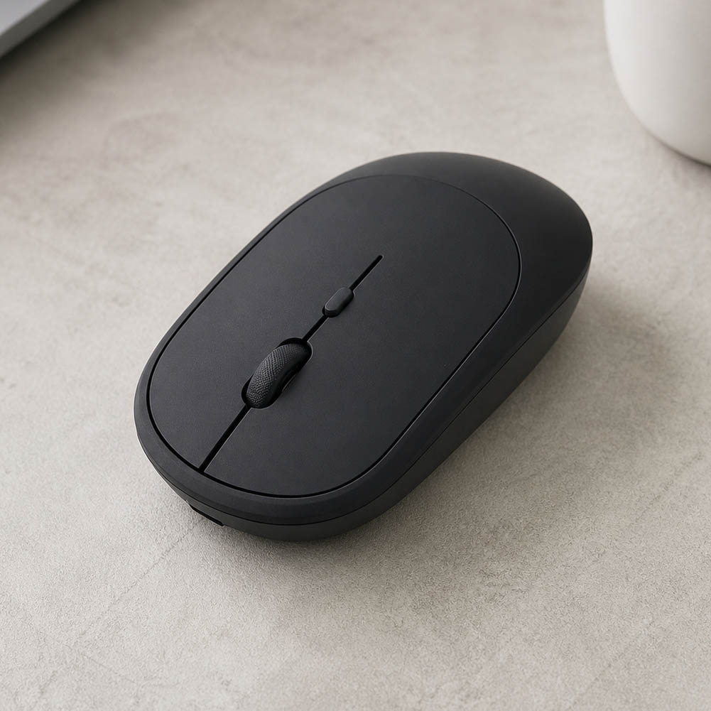 Un mouse inalámbrico recargable negro, de diseño slim y cuatro botones, descansa sobre una superficie clara con acabado minimalista.