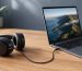 Audífonos negros conectados al puerto de 3,5 mm de un notebook mediante un cable continuo